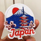 Animated hand holding ten vintage travel and world landmark embroidered stick-on patches