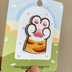 animated hand holding packaged cute cat paw embroidered patches showing three styles and detailed embroidery texture