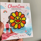 animated hand holding packaged rainbow smiley flower embroidered patches showing two styles and detailed embroidery texture