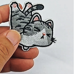 animated hand holding packaged funny everyday tabby cat embroidered patches showing multiple styles and detailed embroidery texture