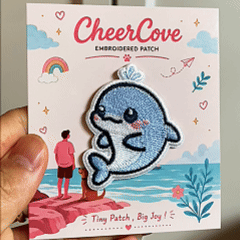 animated hand holding packaged kawaii dolphin embroidered patch showing detailed embroidery texture