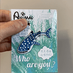 animated hand holding packaged whale shark marine animals embroidered patch showing detailed embroidery texture