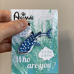 animated hand holding packaged whale shark marine animals embroidered patch showing detailed embroidery texture