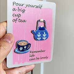 animated hand holding packaged teapot and teacup embroidered patches showing three styles and detailed embroidery texture