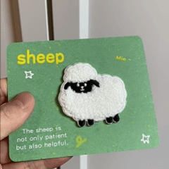 animated hand holding packaged fluffy boucle sheep embroidered patches showing two styles and detailed embroidery texture