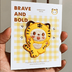 animated hand holding packaged cute kawaii chubby tiger embroidered patches showing three styles and detailed embroidery texture