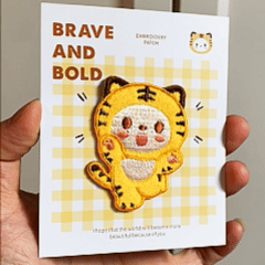 animated hand holding packaged cute kawaii chubby tiger embroidered patches showing three styles and detailed embroidery texture