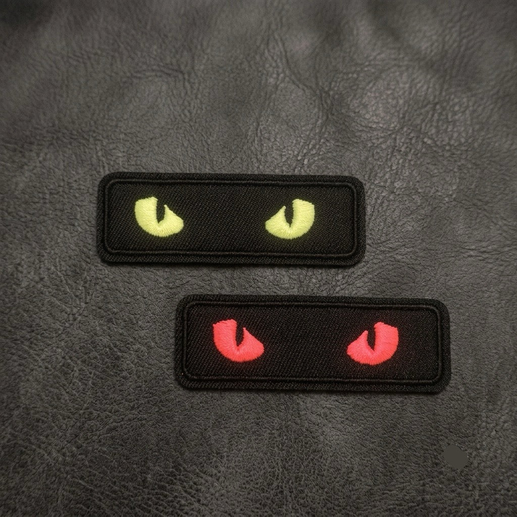 glow-in-the-dark cat eye embroidered stick-on patches — yellow and red on black, 73 × 24mm size reference