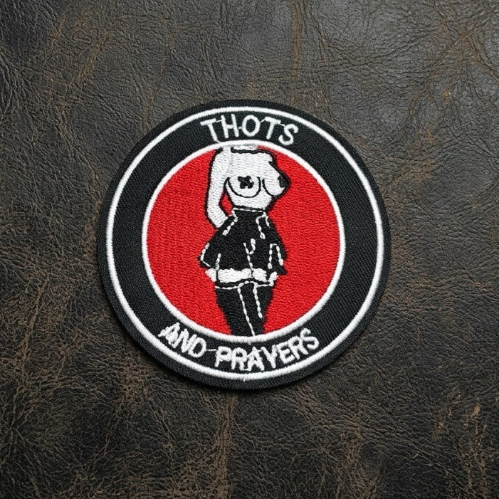 thots and prayers embroidered stick-on patch round punk badge on leather surface — red black and white cartoon figure
