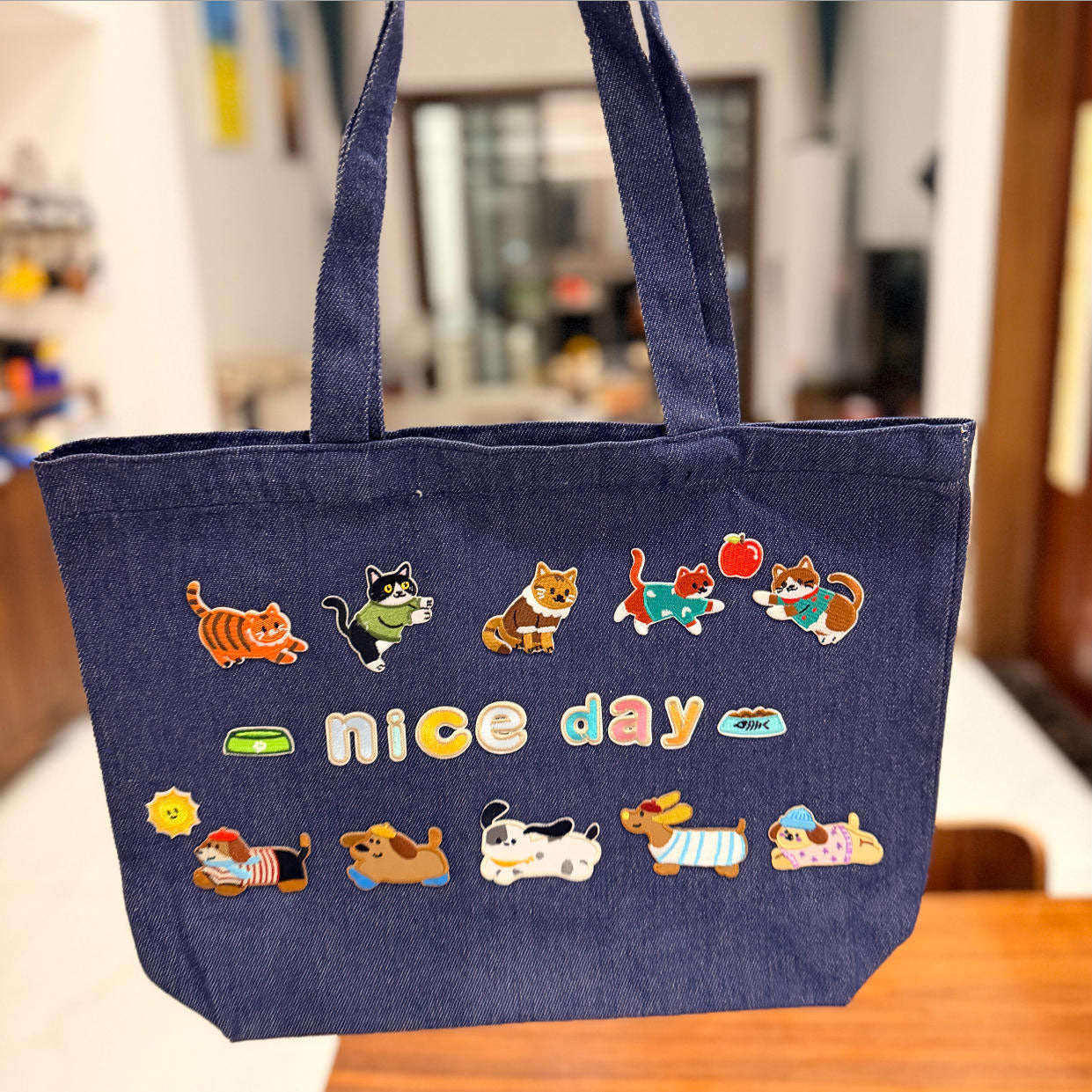 whimsical cat and dog embroidered patches covering a dark denim tote bag