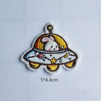 bunny in UFO embroidered stick-on patch — white bunny peering from gold dome flying saucer with star and moon decorations across disc antenna on top 50x44mm