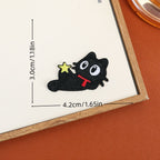 Reclining black cat embroidered stick-on patch with a red scarf and small yellow star
