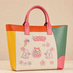 japanese sakura bunny flower basket and cherry blossom stick-on patches decorating a pink and orange color-block leather handbag