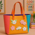 pink cherry blossom and white jasmine floral stick-on patches decorating an orange and yellow color-block leather handbag