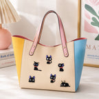 cute big-eyed black cat stick-on patches in various poses decorating a pastel color-block leather handbag