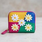 white daisy embroidered patches scattered on a colorblock leather zip coin wallet