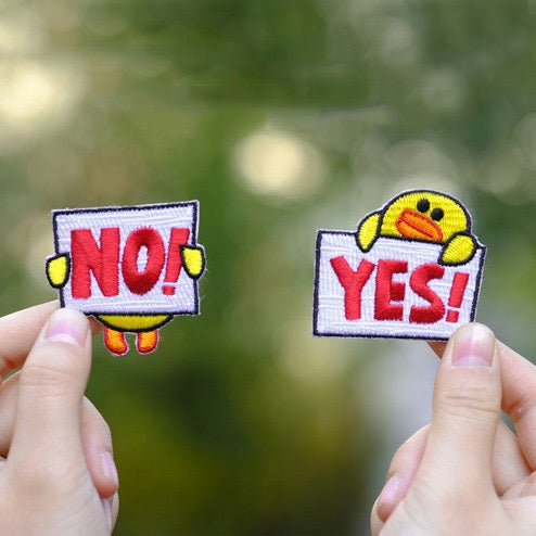 holding a yes or no duck embroidered stick-on patch in hand