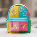 floral letter embroidered patches spelling D Q A M on a colorblock leather mini backpack