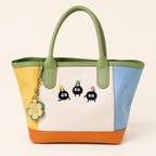 three soot sprite embroidered patches on a green and yellow color-block leather tote bag