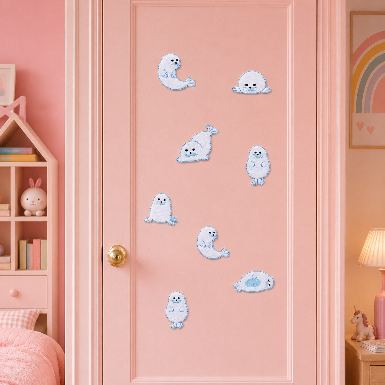 fluffy white harp seal pup stick-on patches with black eyes and blue border stitching in eight poses on a pink door in a pastel girls room