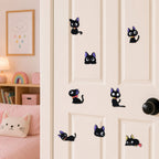 black cat with purple ears and bell collar in sitting walking lying and peeking poses stick-on patches displayed on a white bedroom door