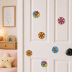 rainbow pink orange yellow blue and purple smiley daisy flower stick-on patches scattered on a white bedroom door