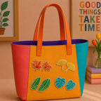 maple ginkgo banana leaf and monstera stick-on patches decorating an orange and yellow color-block leather handbag