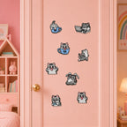 gray tabby cat sitting in blue teacup wearing glasses playing phone lying on back and gaming stick-on patches scattered on a pink door in a girls room
