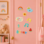 ten rainbow and cute summer embroidered patches with rainbow cloud sunshine flower music notes watermelon and bunny text scattered on a pink bedroom door