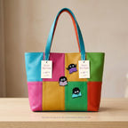 reading soot sprite embroidered stick-on patches on a colorful rainbow stripe leather tote bag