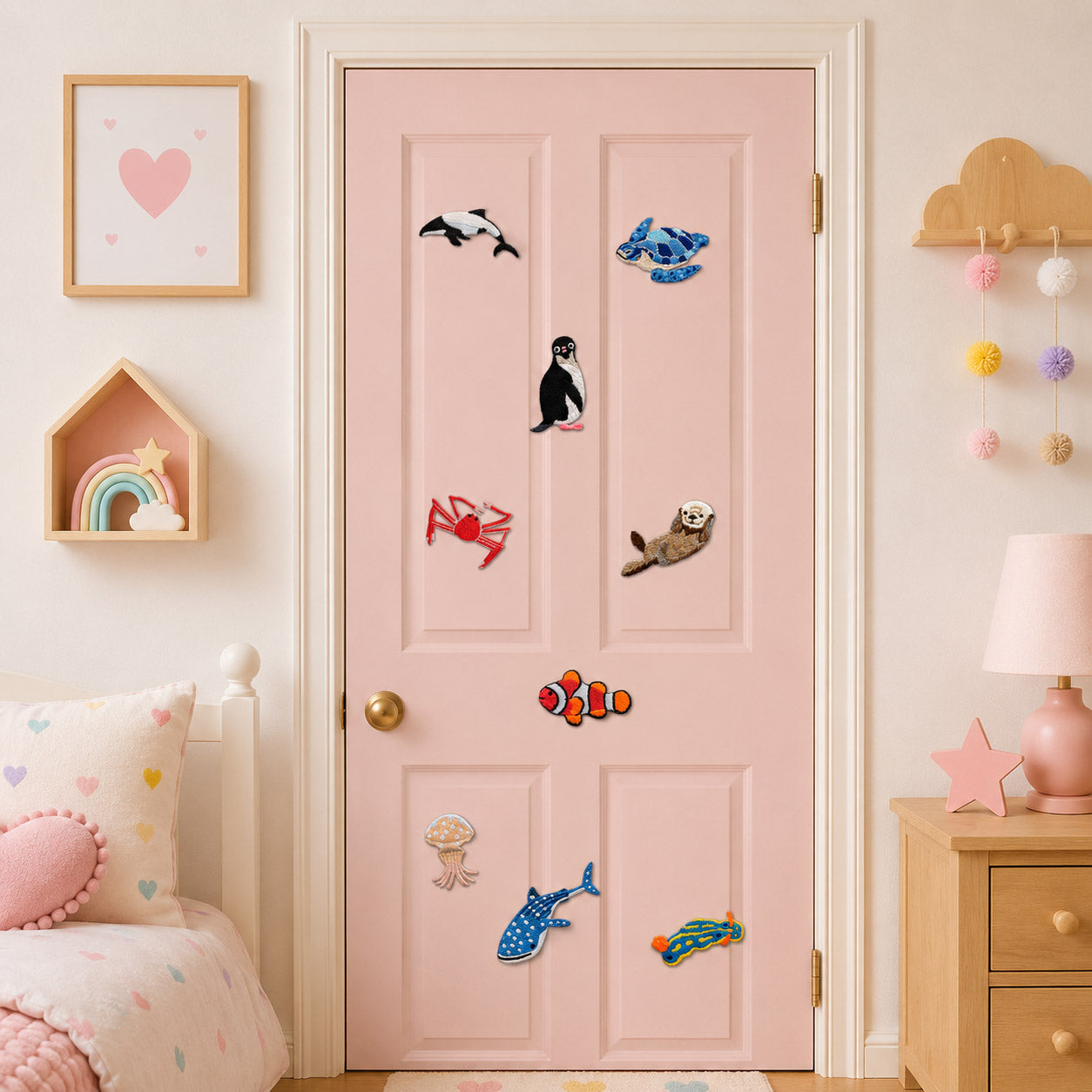 eight marine animal embroidered patches with orca turtle penguin crab otter clownfish jellyfish and whale shark on a pink bedroom door