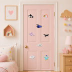 deep sea creature stick-on patches including anglerfish manta ray sea anemone orca dolphin and harp seal scattered on a pink door in a girls room