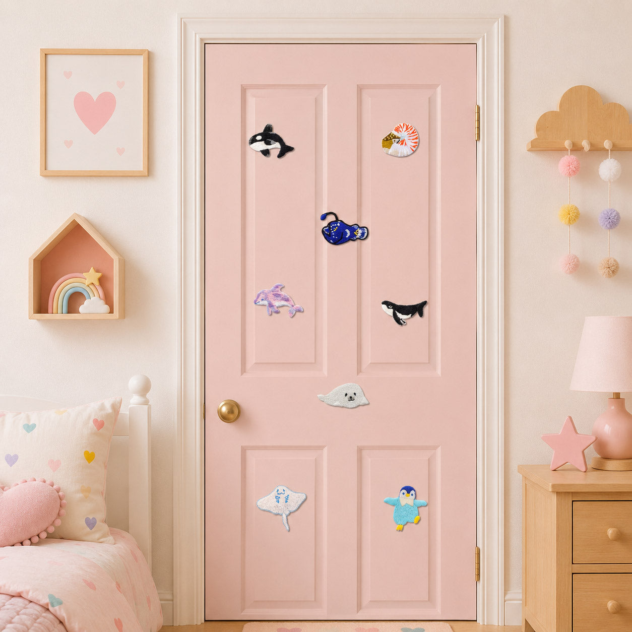 deep sea creature stick-on patches including anglerfish manta ray sea anemone orca dolphin and harp seal scattered on a pink door in a girls room