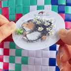 animated peel and stick demo of hedgehog holding lucky clover embroidered patch applied to a woven bag