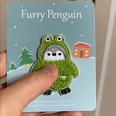 animated hand holding packaged furry penguin embroidered patches showing detailed embroidery texture