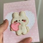 animated hand holding packaged little bunny buddy embroidered patches showing detailed embroidery texture