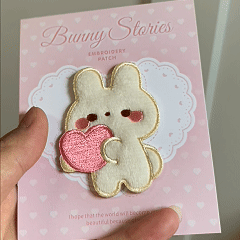 animated hand holding packaged little bunny buddy embroidered patches showing detailed embroidery texture