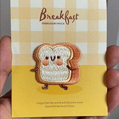 animated hand holding packaged toasty bread kawaii breakfast embroidered patch showing detailed embroidery texture