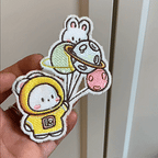 animated hand holding packaged cute space bunny embroidered patches showing multiple styles and detailed embroidery texture