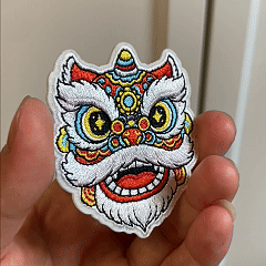 animated hand holding packaged chinese guardian lion dance embroidered patches showing multiple styles and detailed embroidery texture