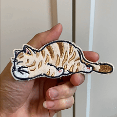 animated hand holding packaged lazy cat embroidered patches showing detailed embroidery texture