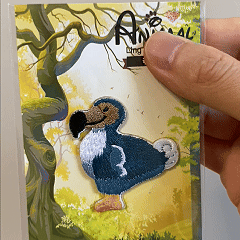 animated hand holding packaged dodo bird sea life marine animal embroidered patch showing detailed embroidery texture