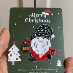 animated hand holding packaged christmas gnome and holiday elements embroidered patches showing three styles and detailed embroidery texture