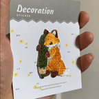 animated hand holding packaged kawaii cute fox embroidered patches showing three styles and detailed embroidery texture